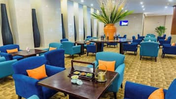 A hotel lobby with multiple seating areas, including sofas and chairs, arranged around tables.