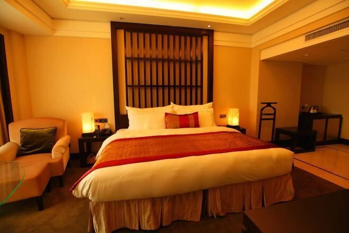 Een hotelkamer met een groot bed, een stoel, een nachtkastje en een bureau.