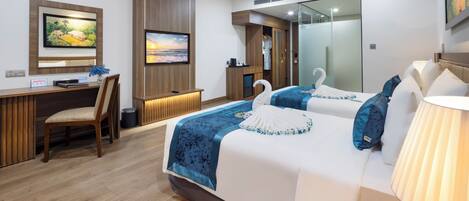A modern hotel room with a large bed, a desk, and a chair. There is a television mounted on the wall and a mirror above the bed.