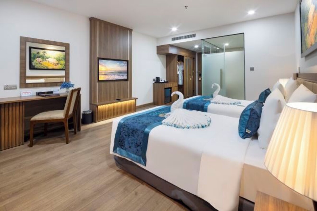 Une chambre d’hôtel équipée d’un lit, d’un bureau, d’une chaise, d’une télévision et d’un miroir.