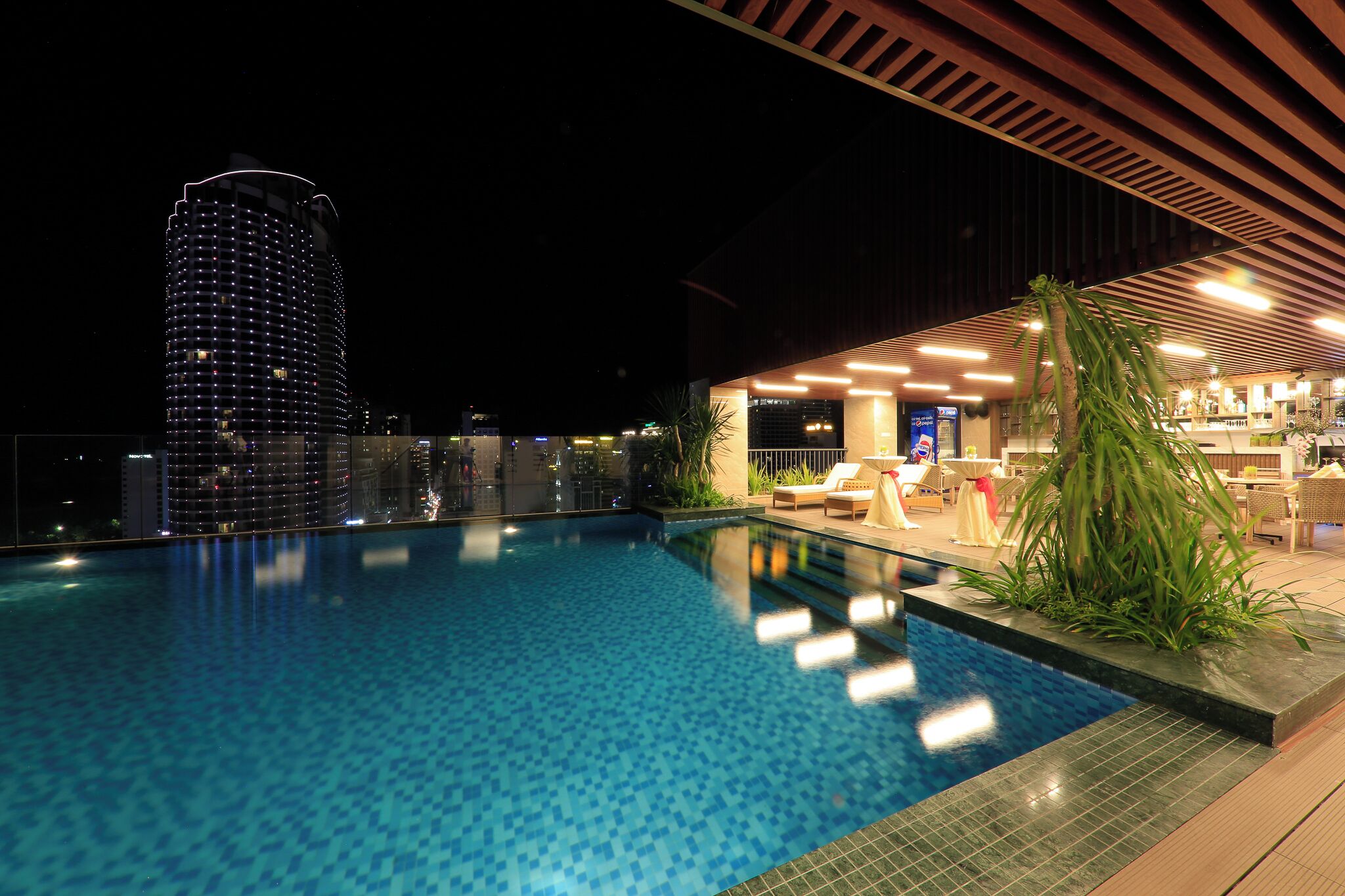 A swimming pool with a view of a tall building at night.