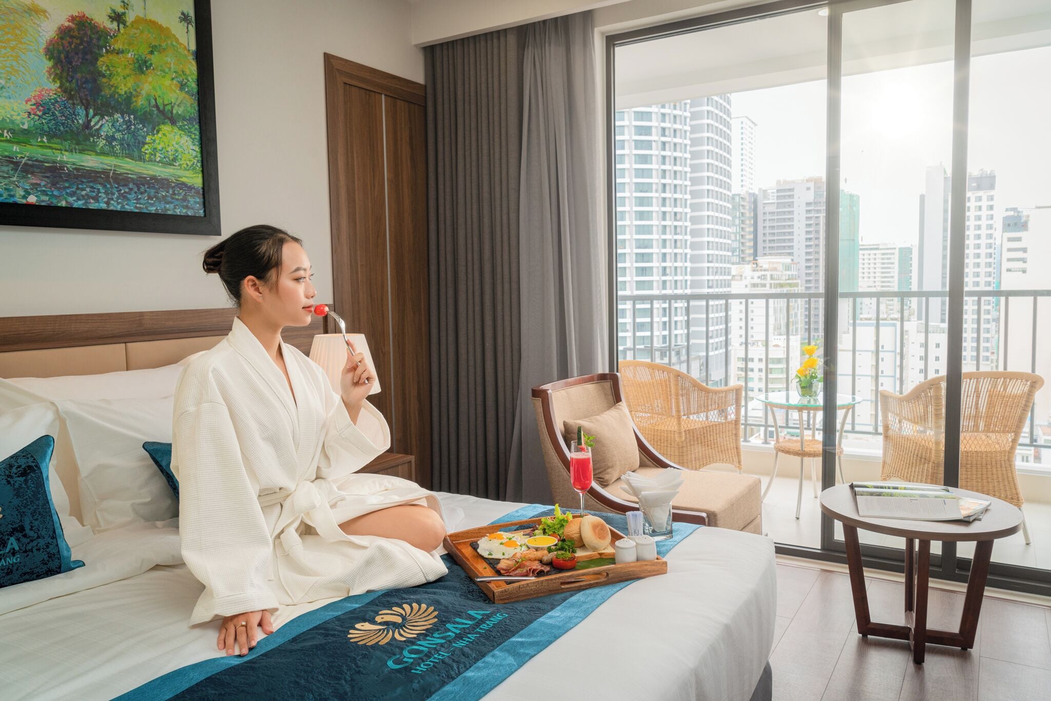 Habitación de hotel con una cama, una bandeja de comida, una bebida y vistas a la ciudad.