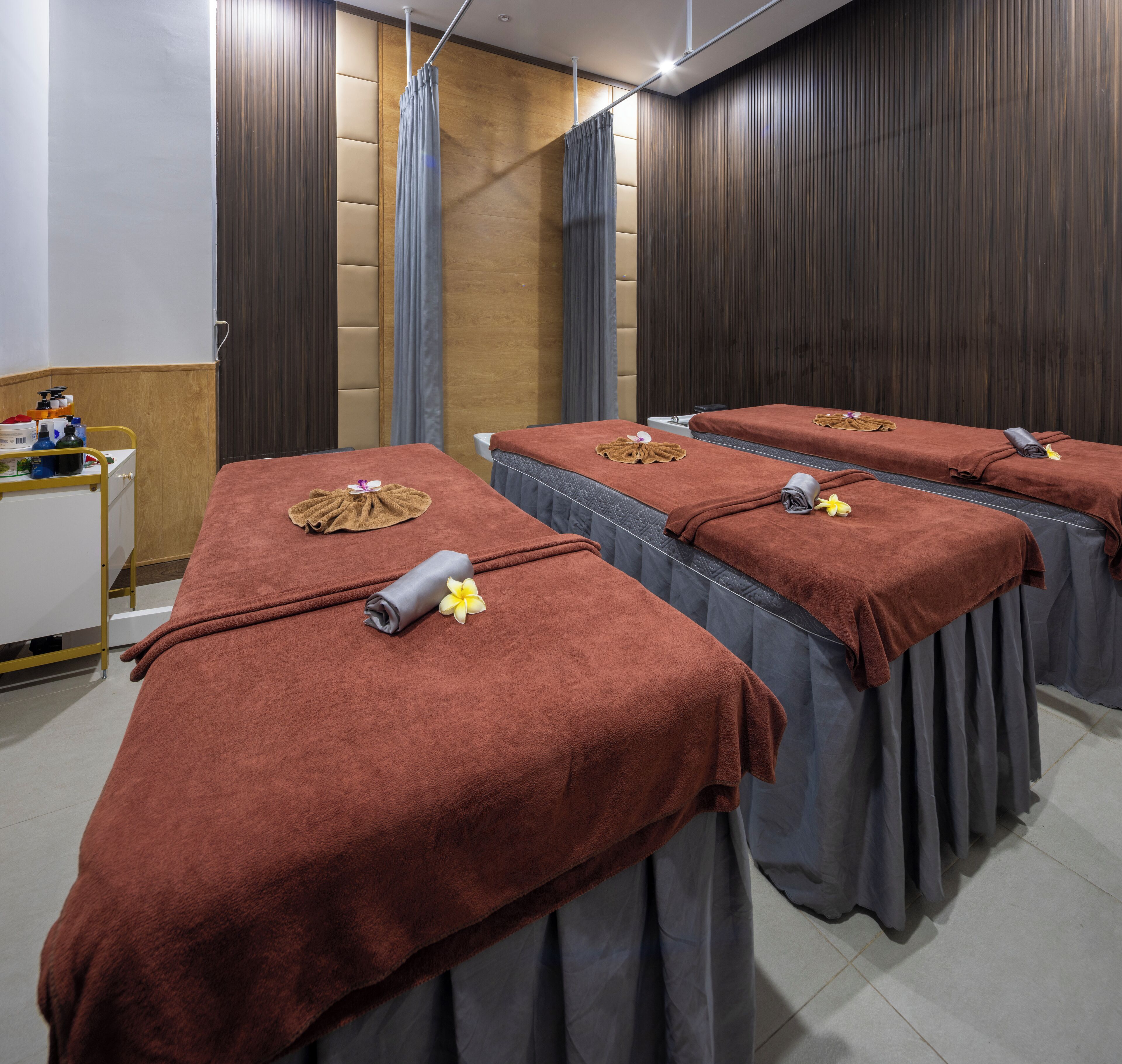 Ett spa-rum med tre massagestolar, var och en täckt med en brun handduk och en blomma.