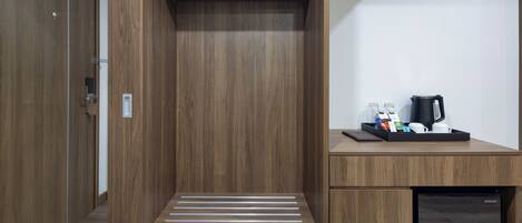 A compact, modern room with built-in storage, a small kitchenette, and a seating area with a bench.