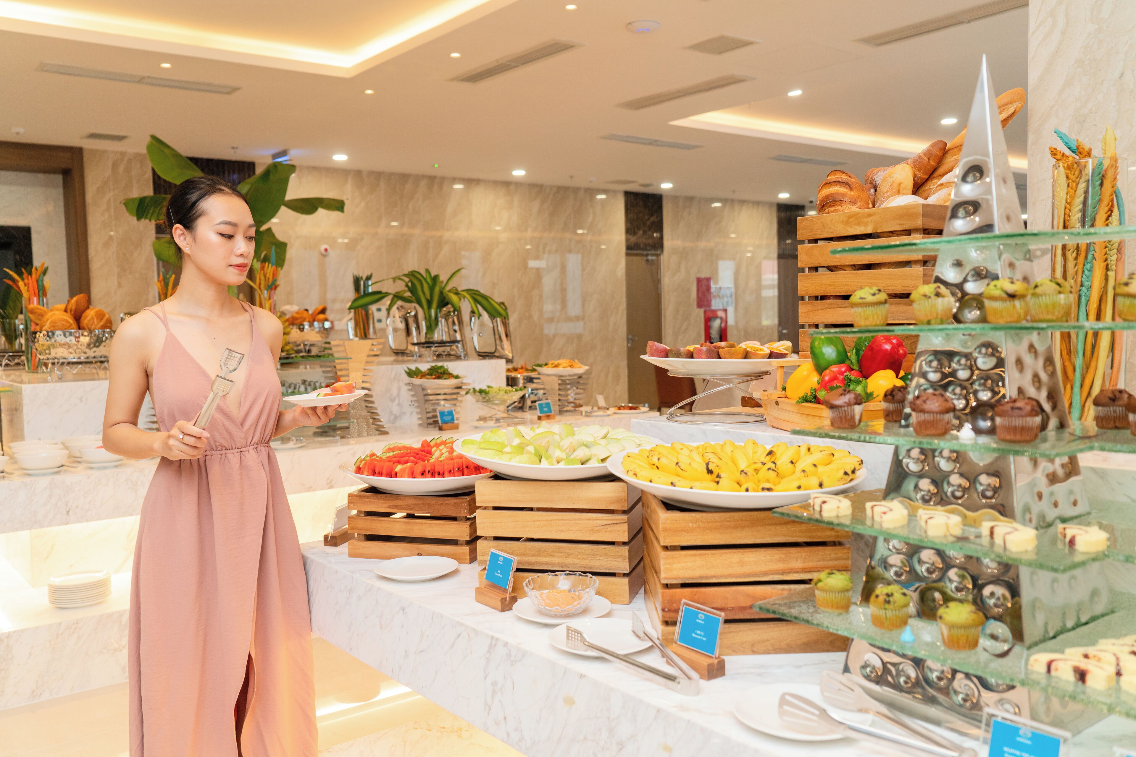 A buffet with various food items and a woman serving.