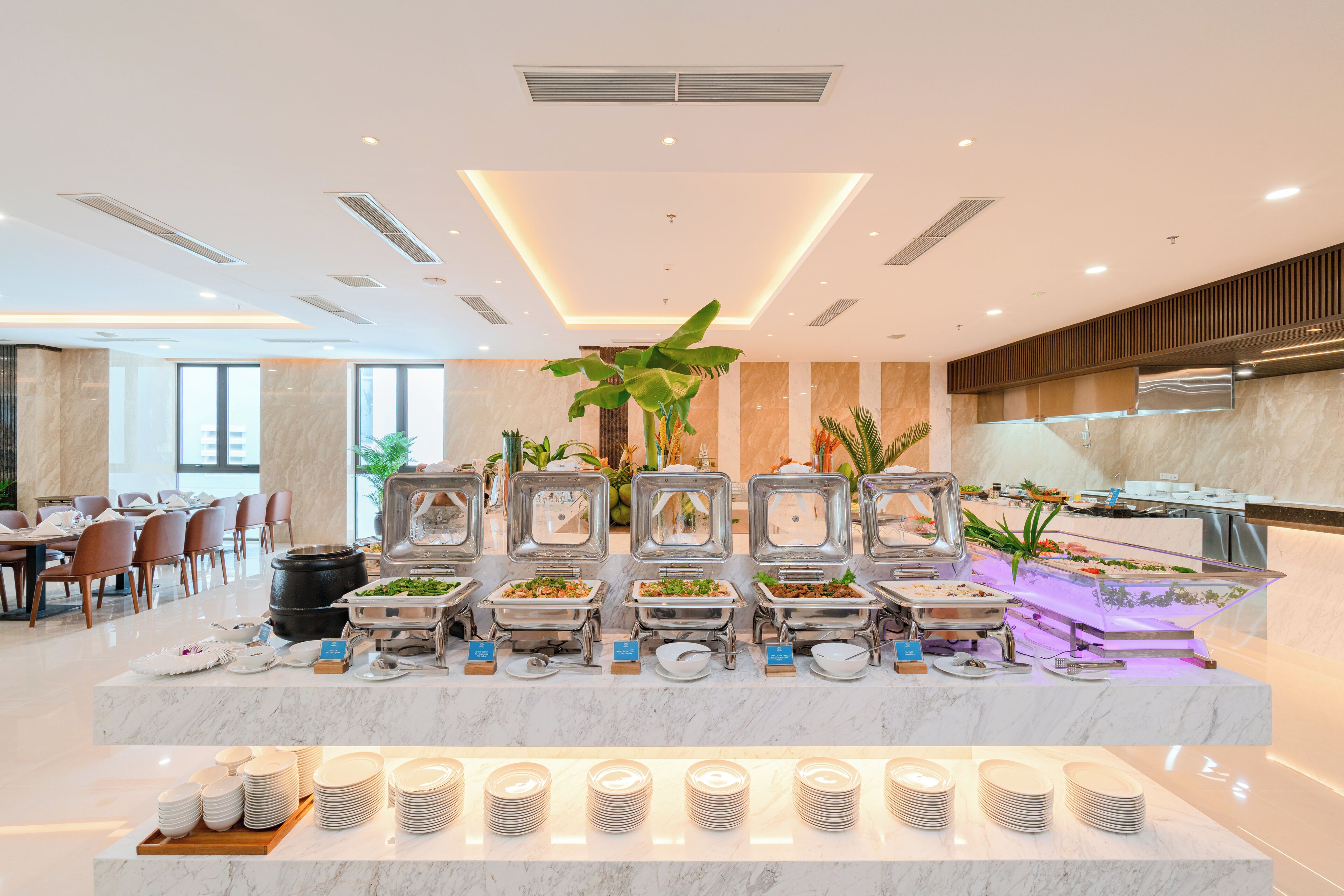 A buffet setup with multiple serving stations, a central decorative plant, and a variety of dishes.