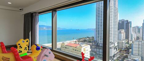 A room with large windows overlooking a cityscape and the sea.