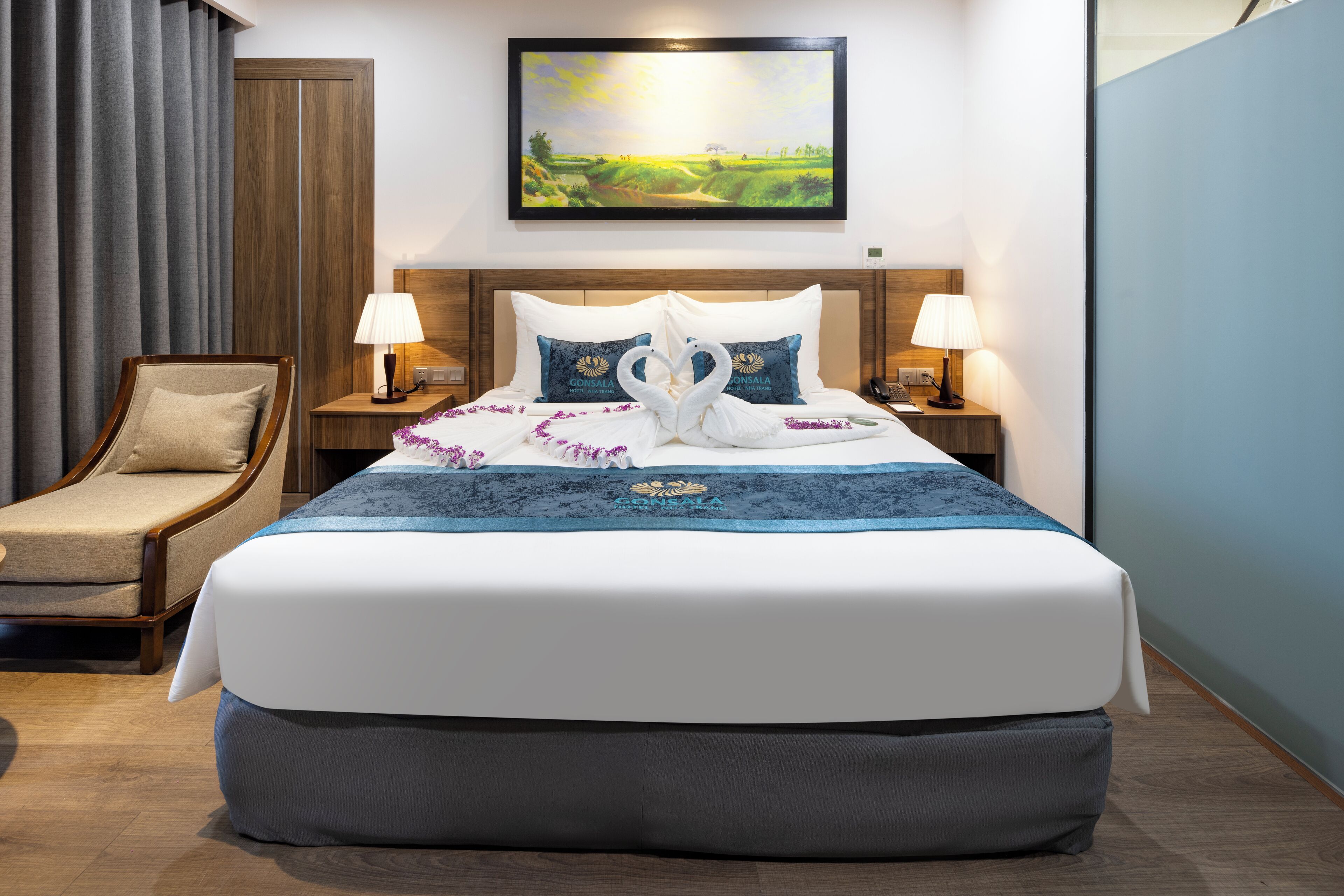 A hotel room with a large bed, two nightstands, a chair, and a painting on the wall.