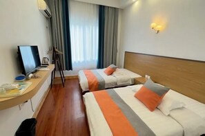 A hotel room with two beds, a desk with a computer, a window with curtains, and a wall-mounted light fixture. - Tianjiale Hotel (Yangshuo)