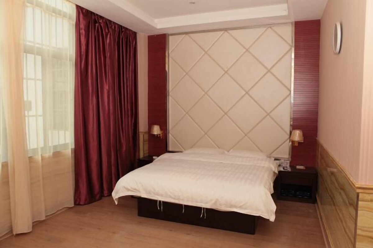 A bedroom with a bed, curtains, a headboard, and nightstands.