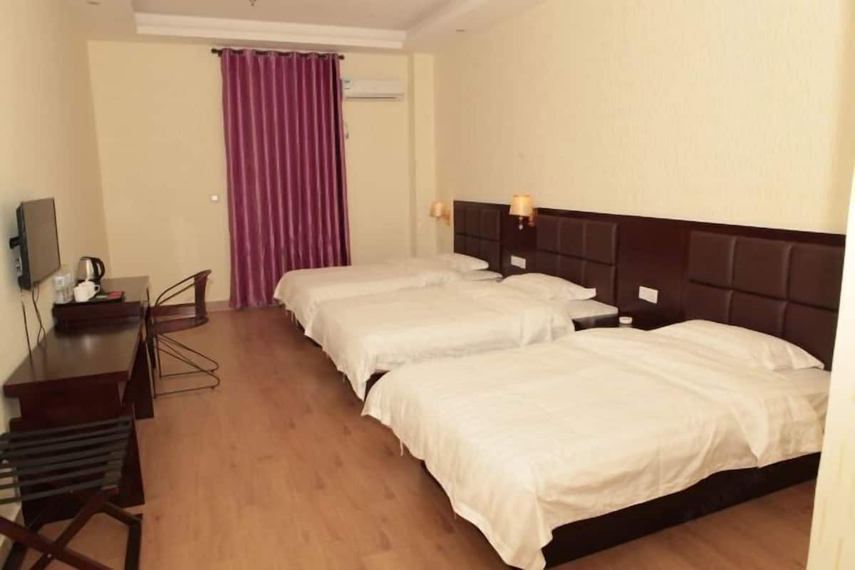 Quarto de hotel com duas camas, uma escrivaninha, uma cadeira e uma televisão.