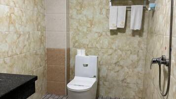 A bathroom with a toilet, a shower, and a towel rack.