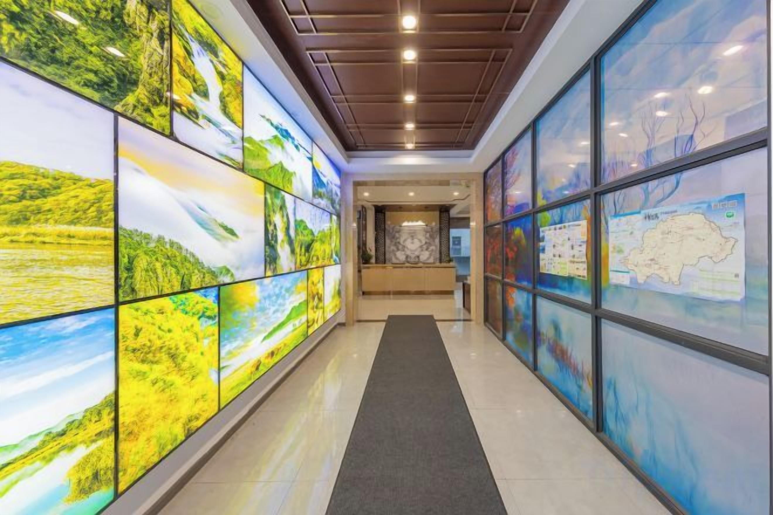 A hallway with large glass panels displaying various landscapes.