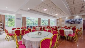 A conference room with round tables and chairs, large windows, and a television screen.