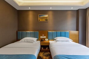 A hotel room with two beds, a wooden headboard, a nightstand, and a painting on the wall.