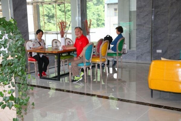 A modern indoor setting with a marble floor, a wooden table, and colorful chairs. - New Beacon Shennongjia Villa (Shennongjia)