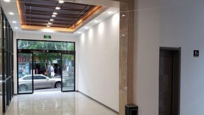 A modern lobby with a glass entrance, a marble floor, and a ceiling with recessed lighting. - New Beacon Shennongjia Villa (Shennongjia)