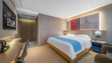 A modern hotel room with a bed, bedside table, chair, and a wall-mounted TV.