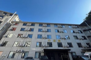 Een meerhoog gebouw met een platte gevel, meerdere ramen en airconditioningsinstallaties.