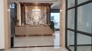 A reception area with a marble counter, a decorative wall, and a glass door leading to another space. - New Beacon Shennongjia Villa (Shennongjia)