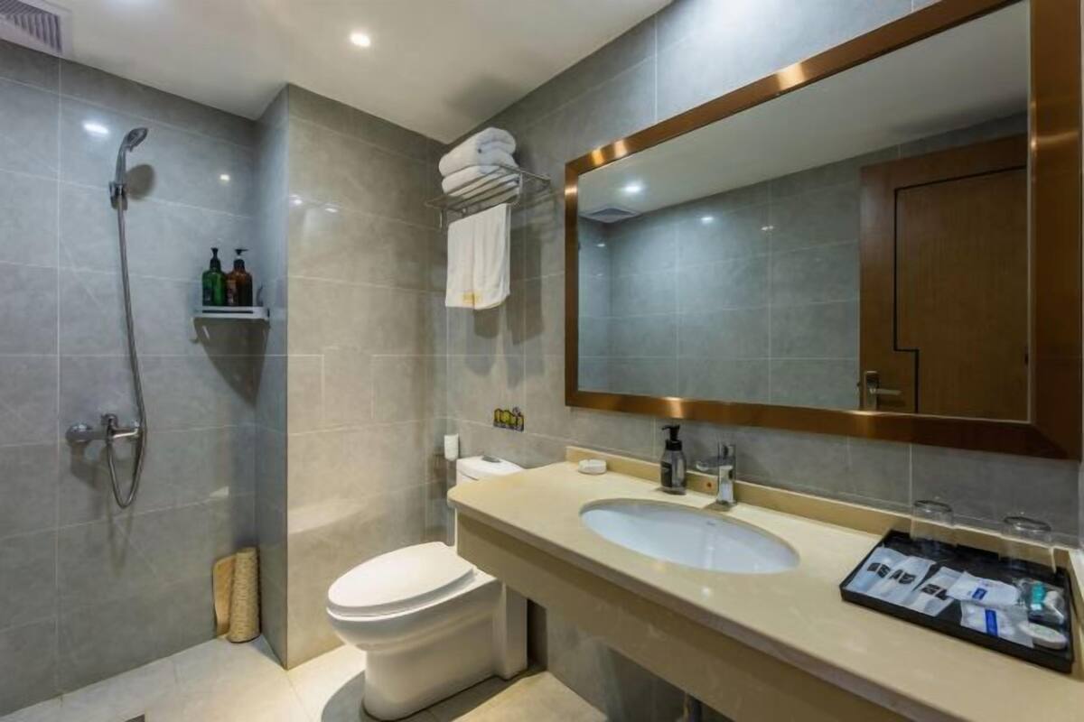 A modern bathroom with a shower, toilet, sink, and a large mirror.