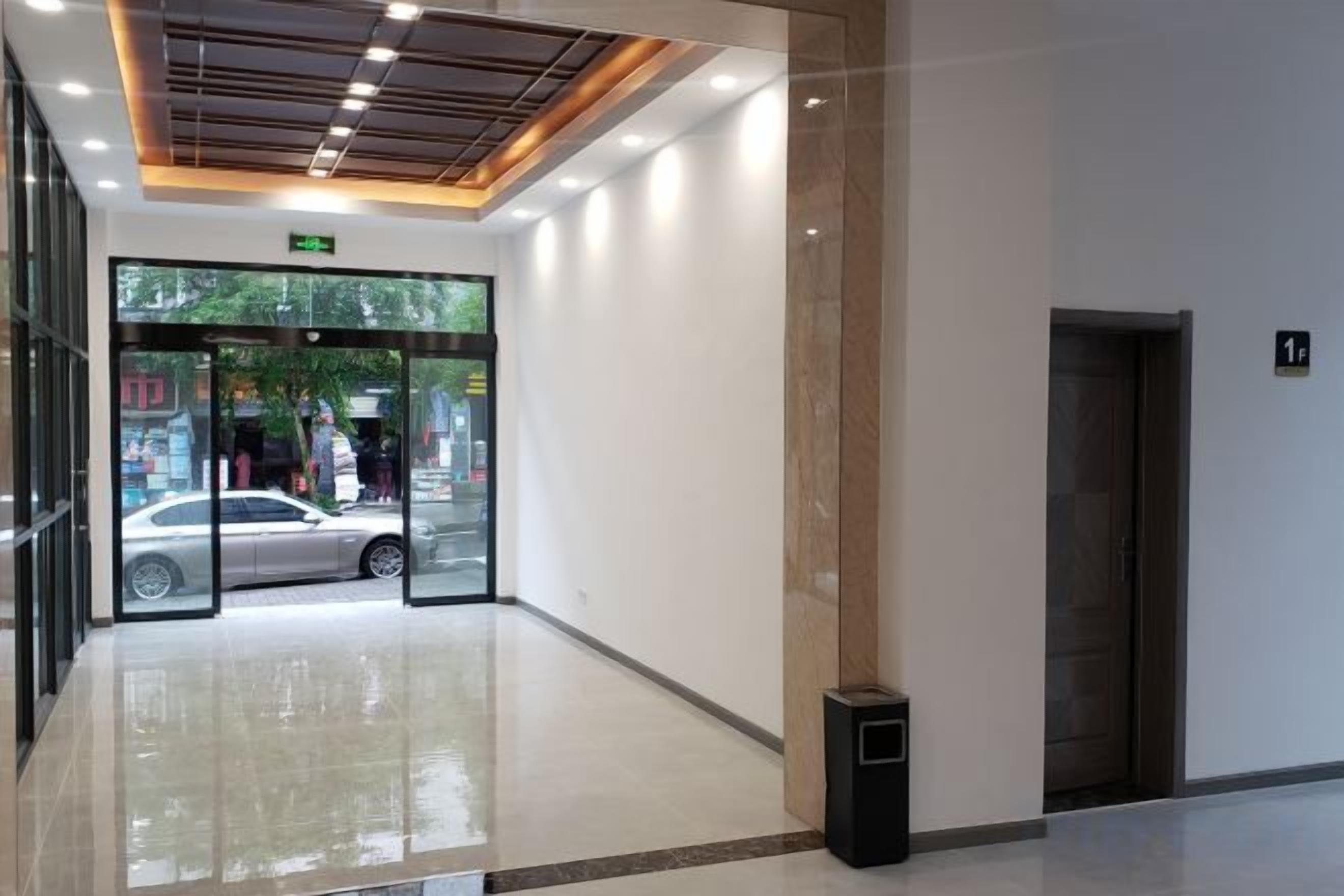 A hotel lobby with a glass entrance, a trash bin, and a door marked with the number 1.