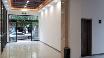 A hotel lobby with a glass entrance, a trash bin, and a door marked with the number 1.