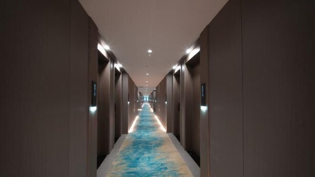 A long, narrow hallway with a patterned carpet and recessed lighting. - New Beacon Shennongjia Villa (Shennongjia)