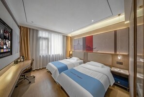 Habitación de hotel con dos camas, un escritorio, un televisor y un ventanal con cortinas.