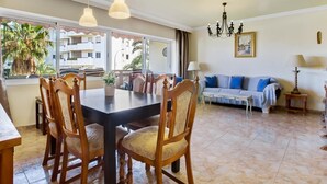 A dining area with a table and chairs, a sofa, a chandelier, and a view of the outside.