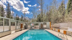 A rectangular indoor swimming pool with clear blue water, surrounded by wooden deck areas and glass walls. - Thunderhead Condo With Heated Pool & Mountain View (Government Camp)