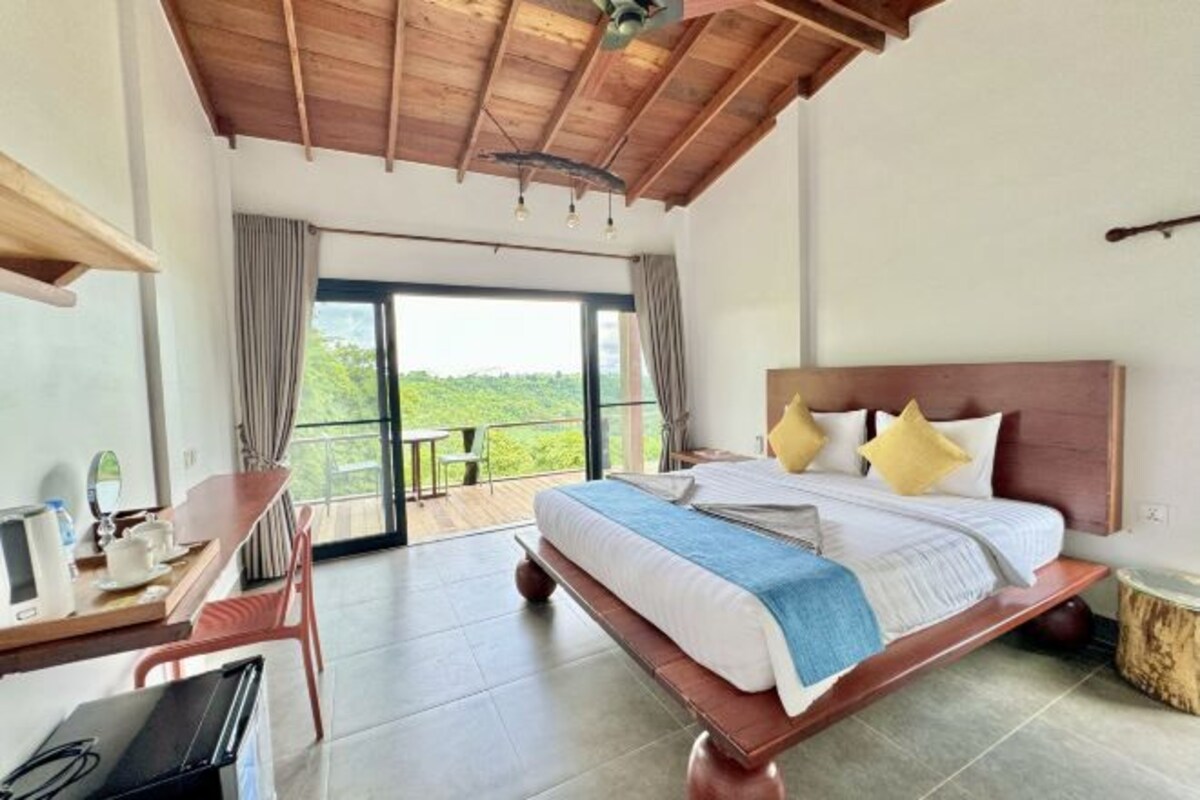Un dormitorio con una cama grande, un escritorio y vistas al exterior.