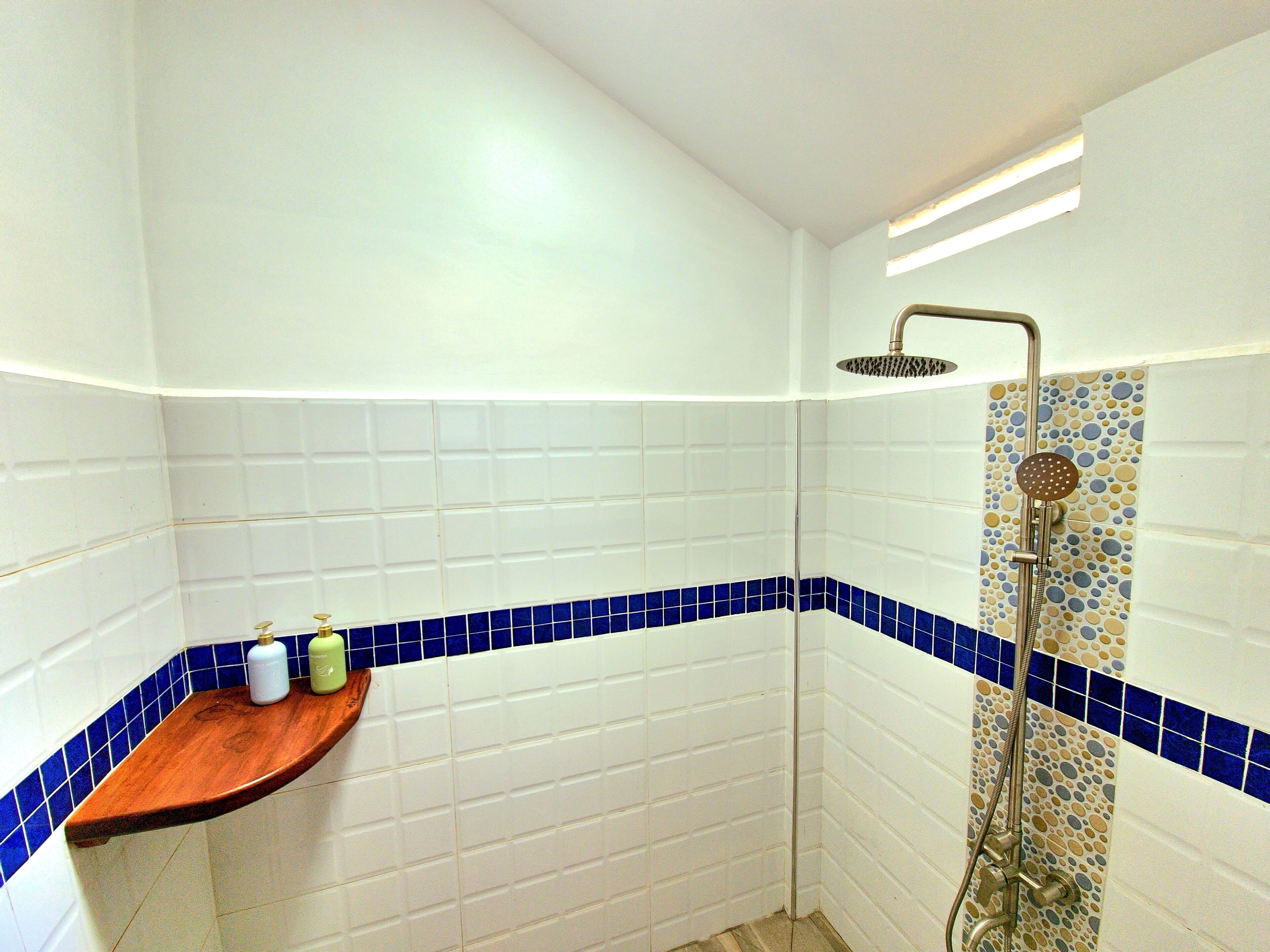 Ein Badezimmer mit weißen Fliesen, einer Holzauskleidung und einer Dusche mit einem dekorativen Fliesendesign.