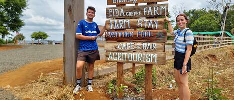 A wooden sign with text indicating a farm stay, cafe, bar, and agritourism.