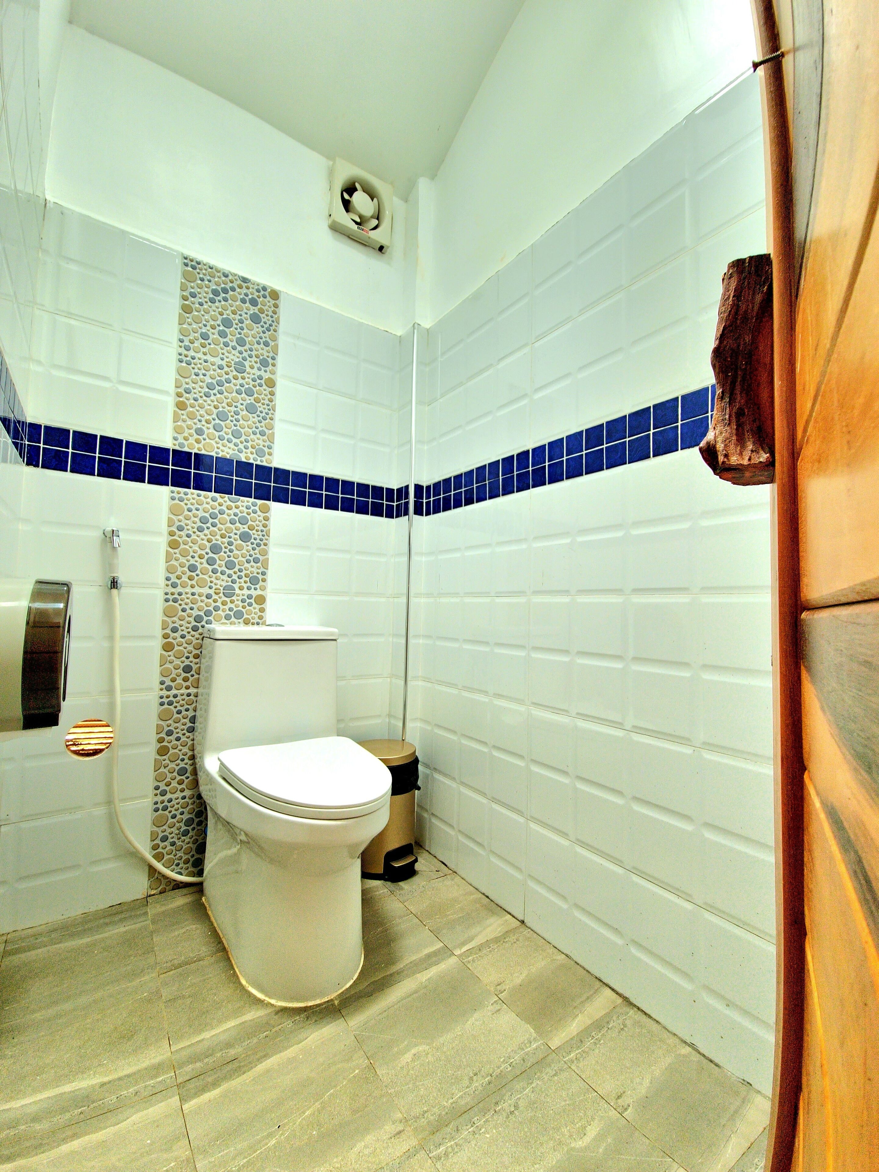 Baño con inodoro, secamanos y cubo de basura.