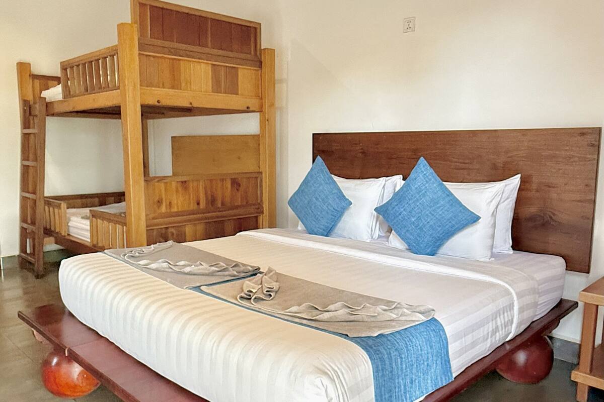 Uma cama beliche com cabeceira de madeira e uma cama simples com estrutura de madeira e base vermelha.
