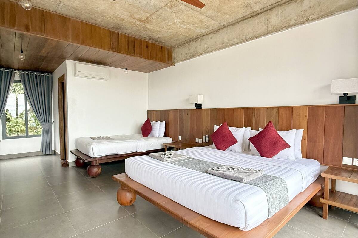 Um quarto espaçoso com uma cama grande, uma cabeceira de madeira, um ventilador de teto e uma mesa de cabeceira.