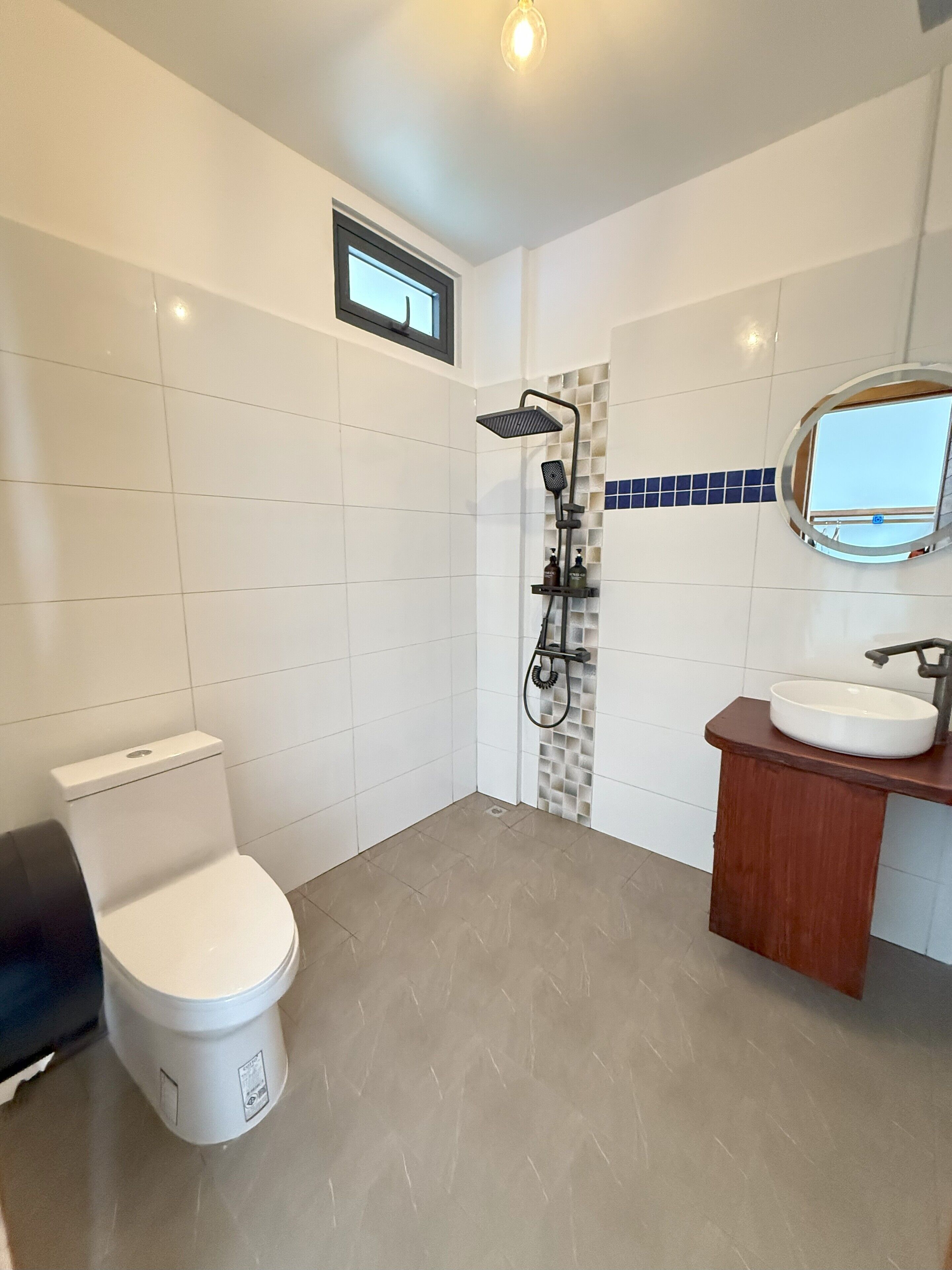 A modern bathroom with a toilet, shower, and sink.