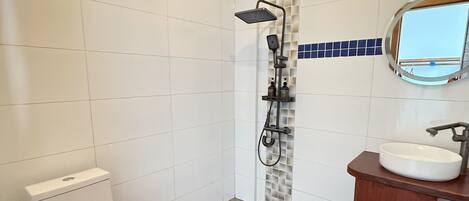 A modern bathroom with a toilet, shower, and sink.