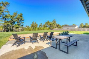 An outdoor patio with a concrete table and four Adirondack chairs. - Gearhart Getaway: Hot Tub + Walk to the Beach (Warrenton)