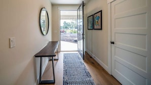 A hallway with a bench, a door, and a view of the outdoors.