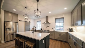 A modern kitchen with a central island, stainless steel appliances, and pendant lighting.