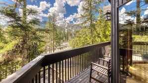 A wooden deck with a railing overlooking a forested area.