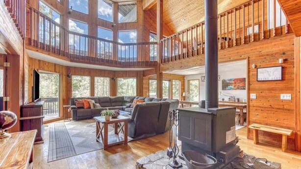 A spacious living area with a fireplace, wooden walls, and a balcony.