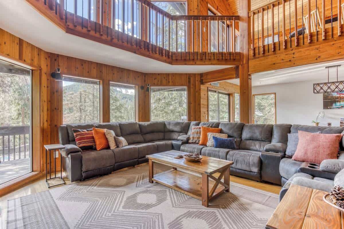 A spacious living room with a large sectional sofa, a coffee table, and a wooden staircase.