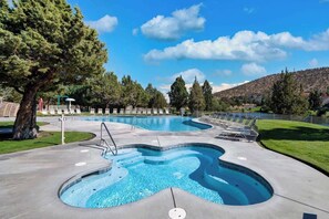 A swimming pool with a wavy design, surrounded by lounge chairs and a tree. - Desert Sky Daydream: Eagle Crest Golf Resort + EV (Redmond)