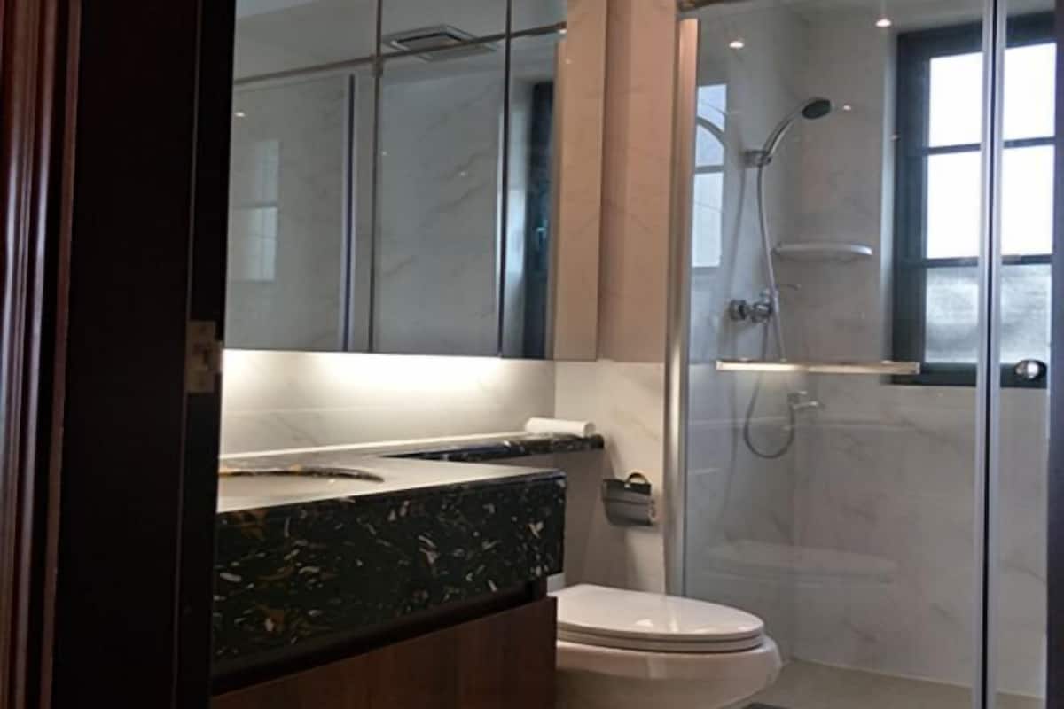 Un baño moderno con cabina de ducha de vidrio, encimera de mármol y un inodoro.