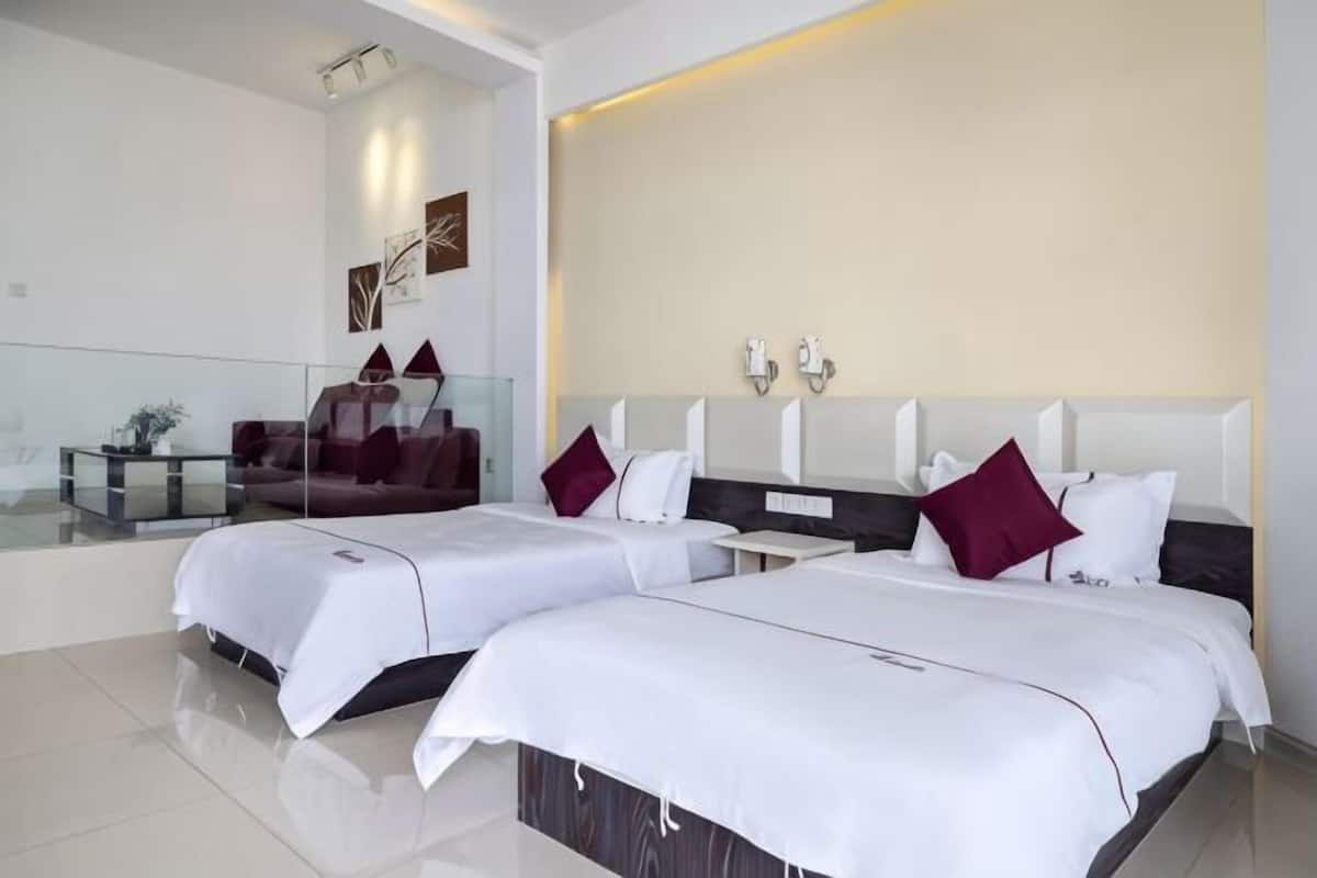 Una habitación de hotel moderna con dos camas, un separador de vidrio, un sofá y un adorno en la pared.