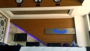 A reception area with a marble counter, clocks, and a sign for 'Bailuwan Dujiagongyu'. - Egret Bay Holiday Apartment (Beibuwan Avenue) (Fangchenggang)