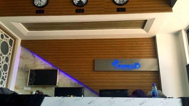Un área de recepción con mostrador de mármol, relojes y un letrero que dice 'Bailuwan Dujiagongyu'.